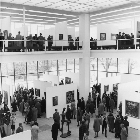 schwarz-weiß Foto aus den 60er Jahren mit Ausstellungsbesuchern, Statuen und Bildern